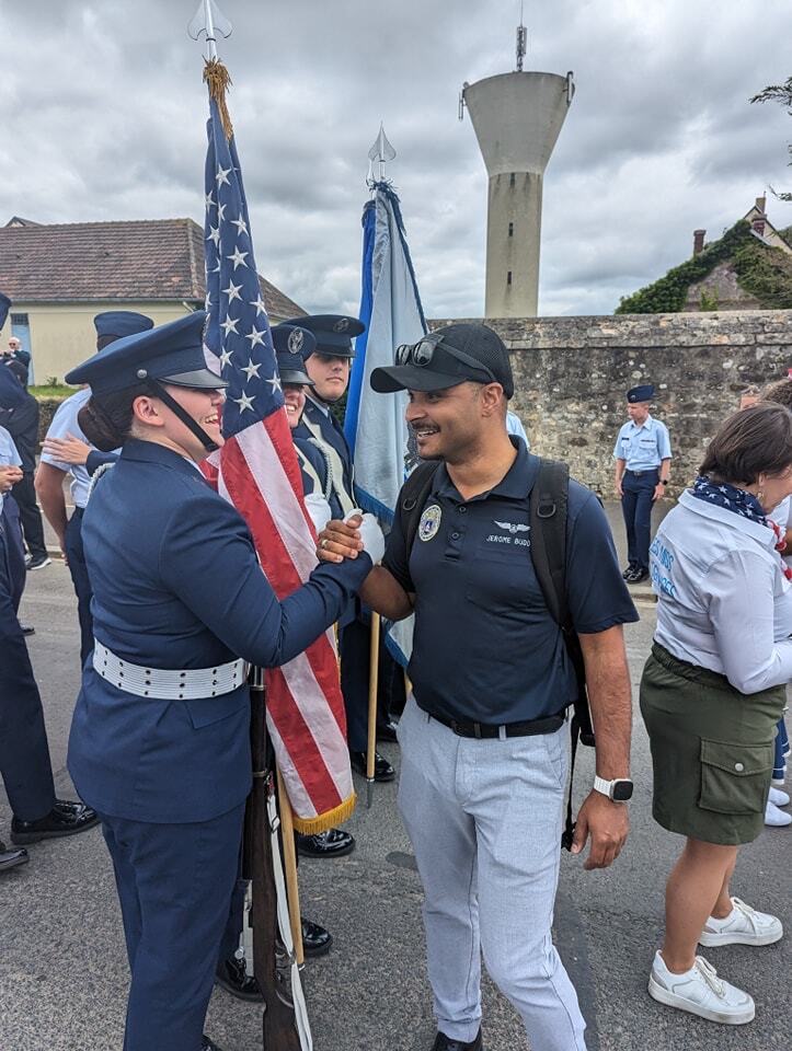 A cadet in service dress shaking hands with a supporter before a commemorative parade in France