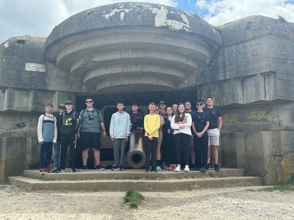 Cadets standing in front of a preserved World War II gun casemate on the Normandy coast