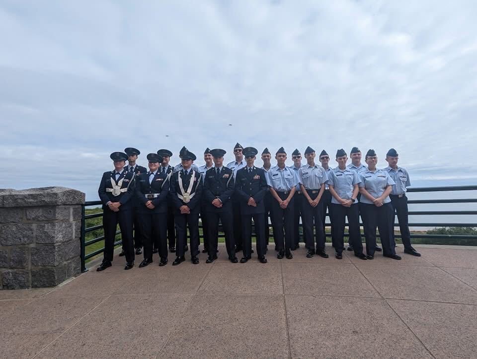 Squadron cadets and senior members in service dress lined up at a coastal overlook in Normandy, France